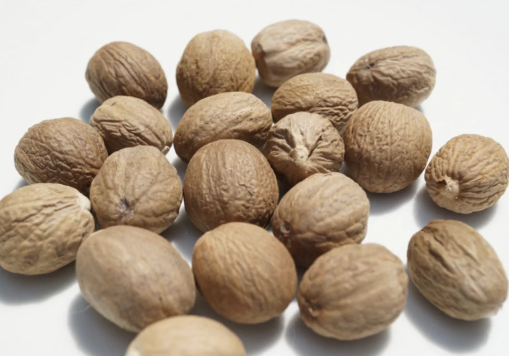 Nutmeg export from Indonesia - whole nutmeg and seeds displayed with spices like star anise and cinnamon, highlighting Indonesia's global nutmeg trade.